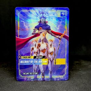 Può includere: Una carta collezionabile olografica con una figura centrale in mantello blu e corona, affiancata da due figure più piccole. La carta mostra il testo TOKEN UNIT, RECRUIT, RECRUIT OF THE ARCANE e la citazione WE ARE THE FUTURE, con un numero 1 nell'angolo.