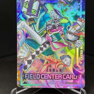May include: A holographic trading card featuring a cartoon character wearing a top hat and holding a gift box. The card has a rainbow background and the text "FIELD CENTER CARD" and "EXTRA MASTER".