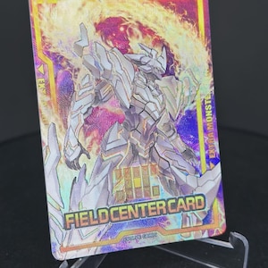 May include: A holographic trading card featuring a silver and black robot with a fiery background. The card is labeled "FIELD CENTER CARD" and "EVOLVE CARD" and has the text "EXTRA MONSTER" in the top right corner.