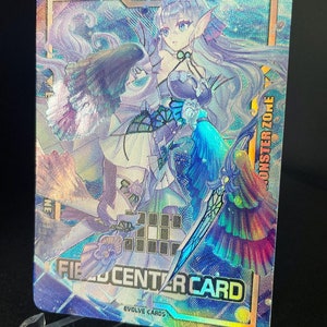 Può includere: Una carta da gioco di scambio olografica con un personaggio femminile con lunghi capelli bianchi e un vestito blu e viola. La carta ha uno sfondo blu e viola con un effetto olografico. Il testo "FIELD CENTER CARD" è stampato sulla carta.