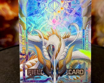 Può includere: Una carta collezionabile olografica con un drago bianco e oro con dettagli intricati. La carta ha uno sfondo blu con le parole "FIELD CARD" e "ULTRA MONSTER". È esposta su un supporto di plastica trasparente.