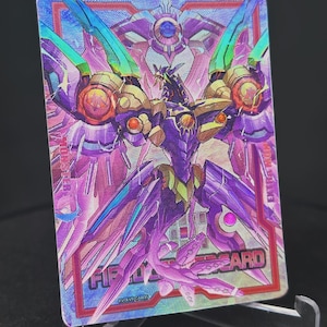 Op de afbeelding: Een holografische trading card met een paarse en gouden robot met vleugels. De kaart heeft een rode rand en de tekst "FIRST CARD" in de rechterbenedenhoek.