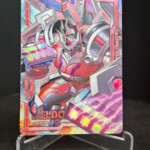 May include: A red and silver robot card with the text "ELDORADO" and "EVOLVE CARDS" on it. The card has a holographic finish and is surrounded by a pink and blue border.