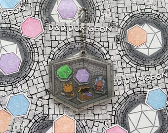 May include: A clear acrylic D&D Dungeon shaker charm keychain. The keychain features a dungeon scene with dice, a treasure chest, and cartoon characters. The background includes colorful dice stickers and the text "D&D Dungeon".
