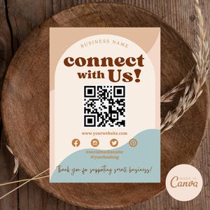 Peut inclure: Une carte de visite avec un code QR, une adresse de site web, des icônes de médias sociaux et le texte "connect with Us!" en brun sur un fond pêche. Le texte "Thank you for supporting small business!" est en brun sur un fond bleu clair. La carte a un logo "Made in Canva" en bas à droite.