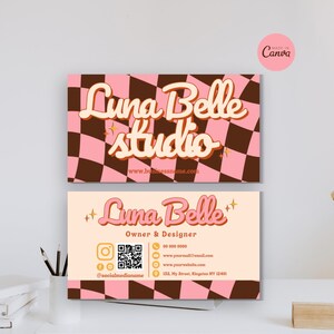 Op de afbeelding: Twee visitekaartjes met een retro-ontwerp. De bovenste kaart heeft een roze en bruine geruite achtergrond met de woorden "Luna Belle studio" in een cursief lettertype. De onderste kaart bevat de naam, eigenaar en contactgegevens.