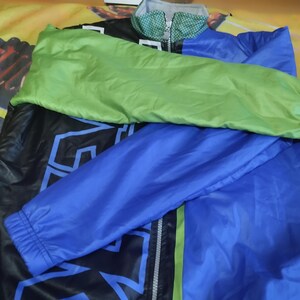 May include: A black, blue, and green jacket with a zipper closure. The jacket has a large graphic print on the front.