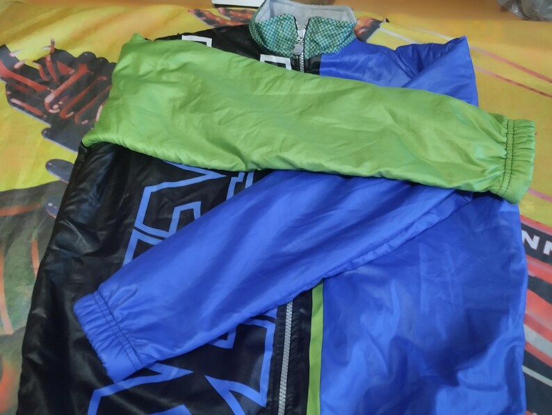 May include: A black, blue, and green jacket with a zipper closure. The jacket has a large graphic print on the front.