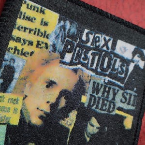May include: A black and white patch with a collage of images and text. The text includes "Sex Pistols", "Why Sid Died", and "Punk Lise is terrible says EP chief".