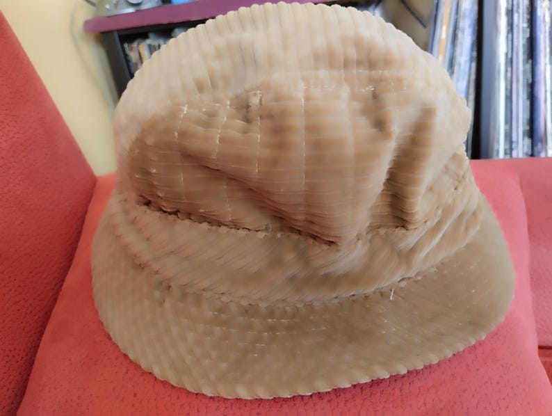 May include: A beige corduroy bucket hat with a wide brim. The hat is made of a soft, textured fabric.