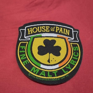 May include: A black patch with the words "HOUSE OF PAIN" in white on a banner. The patch features a shamrock, and the words "FINE MALT LYRICS" in green and yellow. The patch is on a red background.