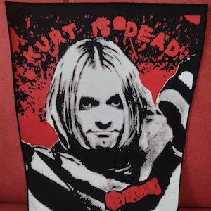 Peut inclure: Patch noir et rouge avec un portrait de Kurt Cobain et le texte "Kurt is Dead!" et "Nevermind".