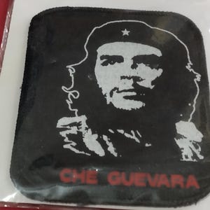 Op de afbeelding: Zwart vierkantige patch met een wit portret van Che Guevara met een baret met een ster. De naam "CHE GUEVARA" is in het rood onderaan gedrukt. De patch heeft een zwarte rand.