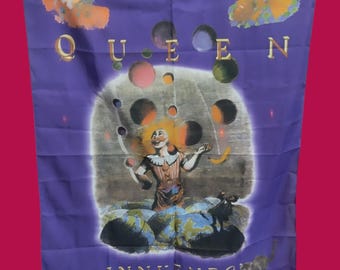 May include: A purple fabric flag with the word "QUEEN" in gold letters and the word "INNUENDO" in gold letters. The flag features a central image of a jester juggling colorful orbs against a dark background. There are four smaller images of jesters in the corners of the flag.