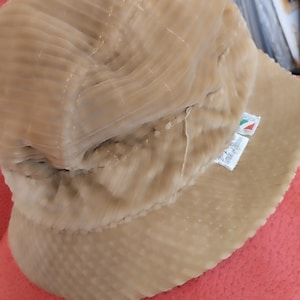 May include: A beige corduroy bucket hat with a small label that reads "Made in Italy".