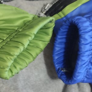 May include: Close-up of the cuffs of a jacket with a green and blue color scheme. The cuffs are made of a soft, quilted fabric.