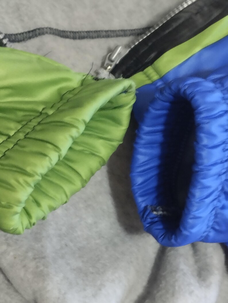 May include: Close-up of the cuffs of a jacket with a green and blue color scheme. The cuffs are made of a soft, quilted fabric.