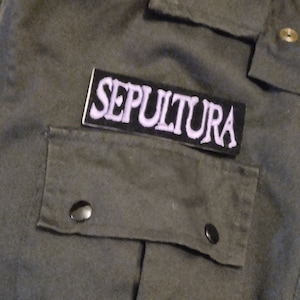 以下が含まれることがあります： 「SEPULTURA」と白く刺繍された文字が書かれた黒いパッチです。