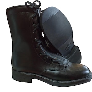 Puede incluir: Botas de combate de cuero negro con diseño de cordones. Las botas tienen una suela resistente y una altura a media pantorrilla. La segunda bota está colocada para mostrar la suela. Diseñadas para durabilidad y protección.