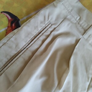 Puede incluir: Primer plano de un pantal&oacute;n beige, que muestra la cintura, los pliegues y los detalles del bolsillo. La tela parece ser un material ligero, con costuras visibles a lo largo de las costuras. El pantal&oacute;n est&aacute; cuidadosamente doblado, lo que sugiere un ajuste a medida.
