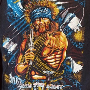 May include: Black graphic t-shirt with a muscular figure in a bandana, holding a gun and pointing. The text "SUICIDAL TENDENCIES" is at the top, and "JOIN THE ARMY" is at the bottom. The design has a vintage, distressed appearance.