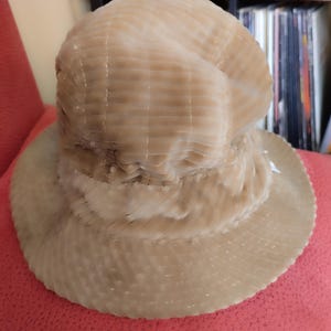 May include: A beige corduroy bucket hat with a wide brim. The hat has a textured, ribbed surface.
