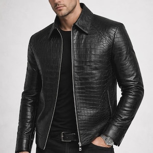 May include: Black leather jacket with a textured, crocodile-like pattern. The jacket has a zipper closure, a collar, and long sleeves. The person is wearing a black shirt, black jeans, and a silver watch.