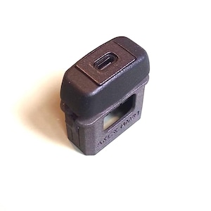 May include: A dark grey, rectangular plastic component featuring a top section with a recessed oval port and a lower section with a hollow centre. The side of the lower section is embossed with the text AKCK M331 in a clear, sans-serif font.