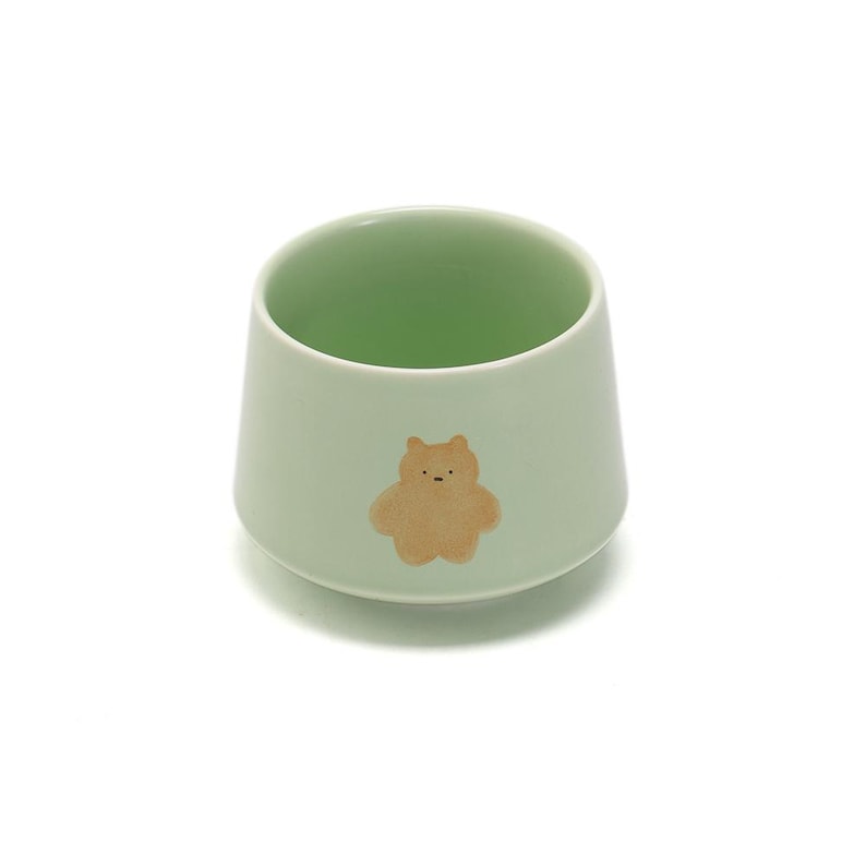 May include: A light green ceramic cup with a brown bear illustration.