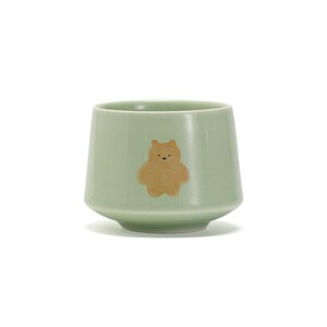 May include: A light green ceramic teacup with a brown bear illustration.
