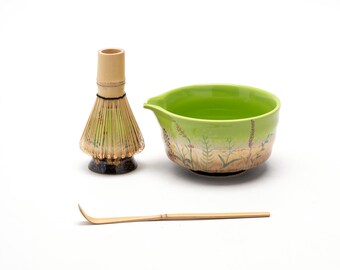 May include: A green ceramic matcha bowl with a floral design, a bamboo matcha whisk, and a bamboo matcha scoop.