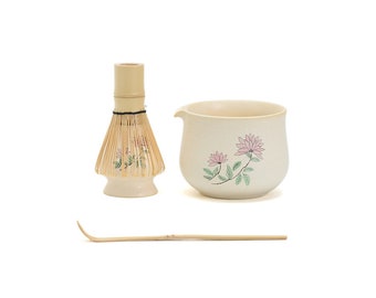May include: A traditional Japanese matcha set with a bamboo whisk, a ceramic bowl with a floral design, and a bamboo scoop.