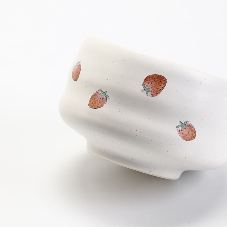 K&ouml;nnte beinhalten: Wei&szlig;e Keramiksch&uuml;ssel mit welligem Design und einem Muster aus roten Erdbeeren.