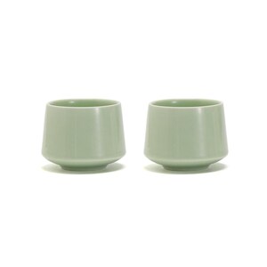 May include: Two pale green ceramic cups with a rounded bottom and a slightly flared lip.