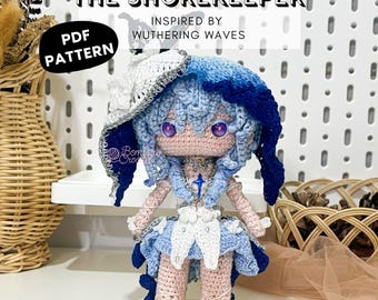 May include: A handmade crochet doll, "The Shorekeeper," inspired by "Wuthering Waves." The doll features a blue and white color scheme, with a detailed hat, dress, and hair. The doll is displayed on a wooden stand. The image includes the text "PDF PATTERN."