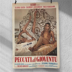 May include: Vintage Italian movie poster for "Pecatti di Gioventu" featuring actresses and text. The poster is printed on aged paper and is hanging against a white wall. The poster's title is in large red letters.