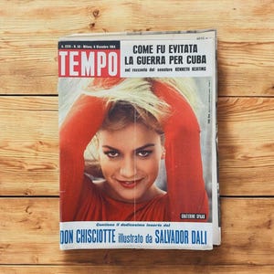 May include: A vintage Italian magazine, Tempo, from December 1964, featuring a woman on the cover with red clothing. The headline reads "COME FU EVITATA LA GUERRA PER CUBA". The magazine also mentions "DON CHISCIOTTE illustrato da SALVADOR DALI".