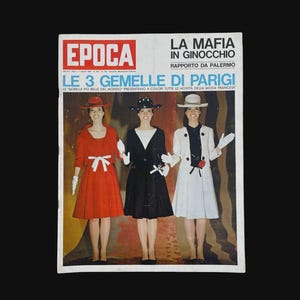 May include: Vintage magazine cover featuring three women in stylish outfits. The cover includes the title "EPOCA" in a red box, and Italian text. The women are wearing dresses in red, black, and white, each with matching hats and gloves.