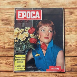 May include: Vintage Italian magazine cover featuring a woman with red hair and a blue dress, holding flowers. The magazine title "EPOCA" is in a red box. Text includes "Scongiurato a Viterbo", "92 PAGINE", and "LE AUTO DEL 1954".