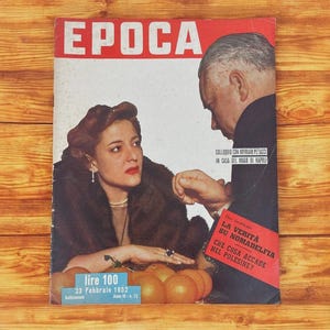 May include: Vintage Italian magazine cover featuring the word "EPOCA" in red. The cover shows a woman in a fur coat and a man in a suit. Text includes "lire 100" and "23 Febbraio 1952."