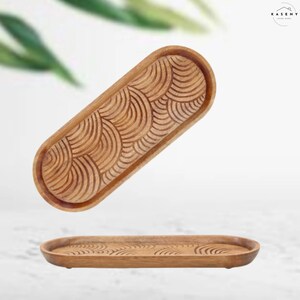 May include: A wooden tray with a carved wave pattern. The tray is oval shaped and has a natural wood finish.