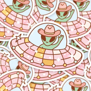 May include: A set of colorful stickers featuring cartoon aliens wearing cowboy hats and flying in pink and white spaceships. The stickers are perfect for adding a fun and quirky touch to laptops, water bottles, or journals.