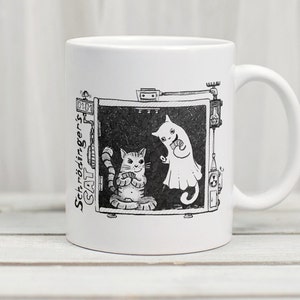 May include: White ceramic mug with a black and white illustration of a cat in a box with a ghost cat. The text "Schrödinger's CAT" is written on the side of the box.