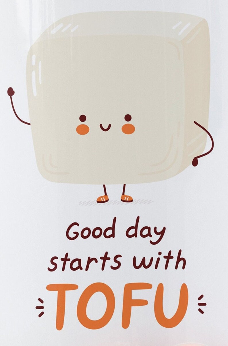 Może przedstawiać: Biały blok tofu z uśmiechającą się twarzą, ramionami i nogami. Tofu ma na sobie pomarańczowe buty. Tekst "Good day starts with TOFU" jest napisany pod tofu.