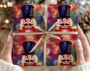 May include: A wrapped gift featuring a repeating pattern of a nutcracker soldier with a black top hat, white hair, and a mustache. The wrapping paper has a colorful, abstract background. The gift is tied with a cream-colored ribbon.