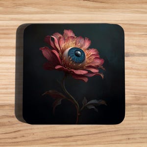 Könnte beinhalten: Ein quadratischer Untersetzer mit einem surrealen Bild einer Blume mit einem menschlichen Auge in der Mitte. Die Blume hat rote Blütenblätter und eine blaue Iris. Der Hintergrund ist dunkel und erzeugt einen starken Kontrast.