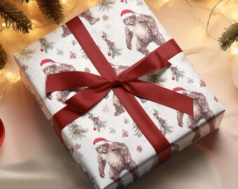 Puede incluir: Un regalo envuelto con papel blanco con un diseño de Bigfoot con gorros de Papá Noel y árboles de Navidad. El regalo está atado con una cinta y un lazo burdeos, perfecto para la temporada navideña.