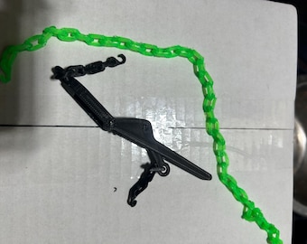 May include: A black plastic chain hoist with a green chain. The chain hoist is a small, hand-operated device used to lift and lower objects.