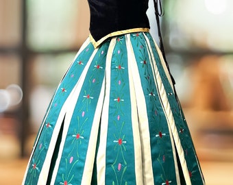 May include: A teal and cream dress with a black bodice and gold trim. The bodice features a floral design. The skirt has vertical cream stripes with teal panels, decorated with floral embroidery. The dress has blue shoulder detailing.