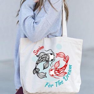 May include: Cream-colored tote bag featuring a black and white koi fish and a red koi fish in a yin-yang design. The text "Swim For The Dream" is printed in red and teal. The bag has a simple, minimalist design.